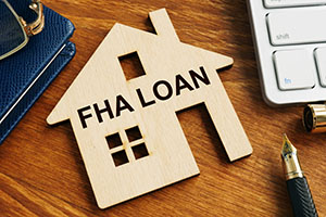FHA Loan written on a cardboard cutout of a home sitting on a desk.